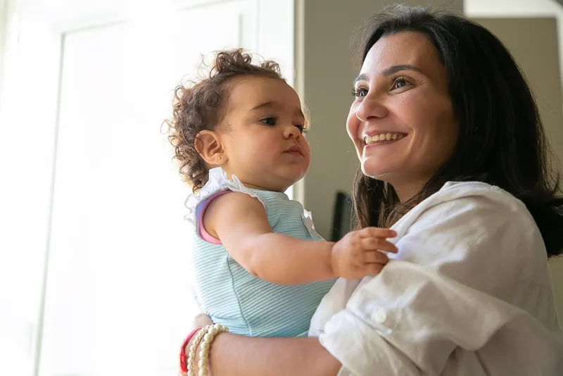 Foto ilustrativa de uma mãe segurando sua bebê no colo